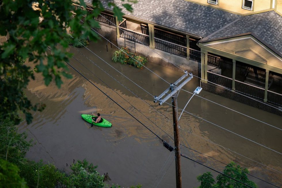 A kayaker paddles down a flooded street.