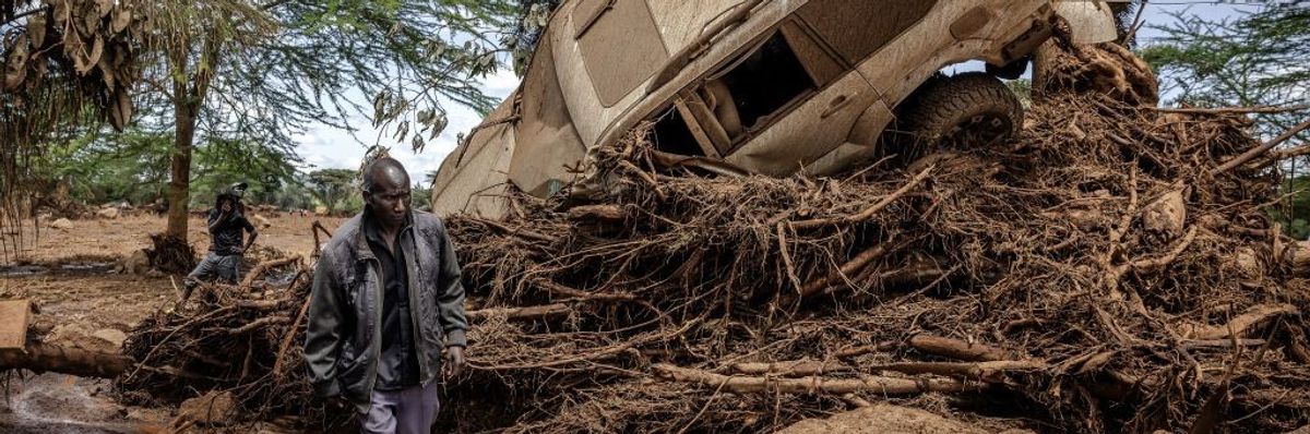 a Kenyan man walks by an SUV tossed about by floodwaters