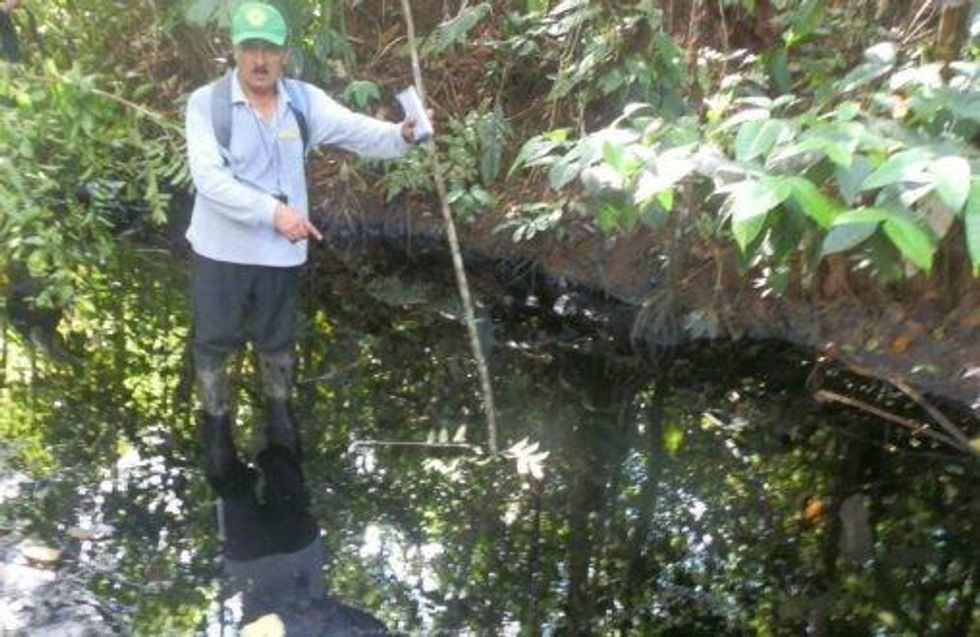A local wades into an oily stream without any protective equipment. (Photo: Mongabay)