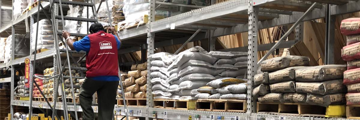 A Lowe's worker climbs down a ladder