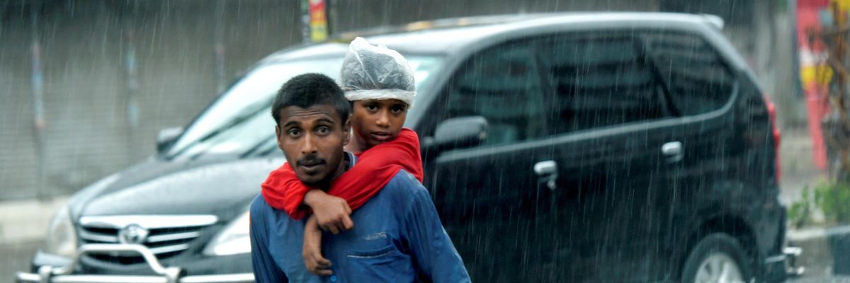 A man and his child attempt to flee a flooding street in Bangladesh