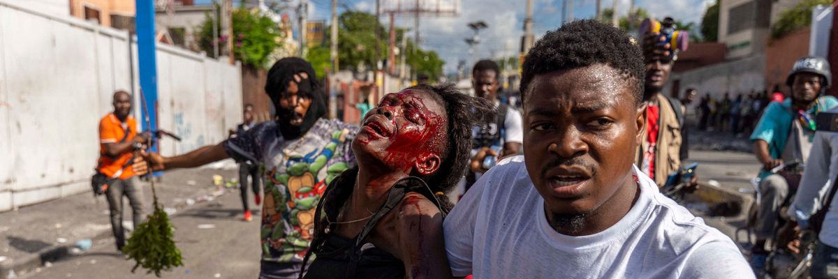 A man assists an injured woman during a protest demanding the resignation of Haitian Prime Minister Ariel Henry in Port-au-Prince, Haiti on October 10, 2022.