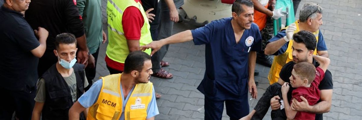 A man carries a child into a hospital in Gaza as medical workers rush around.