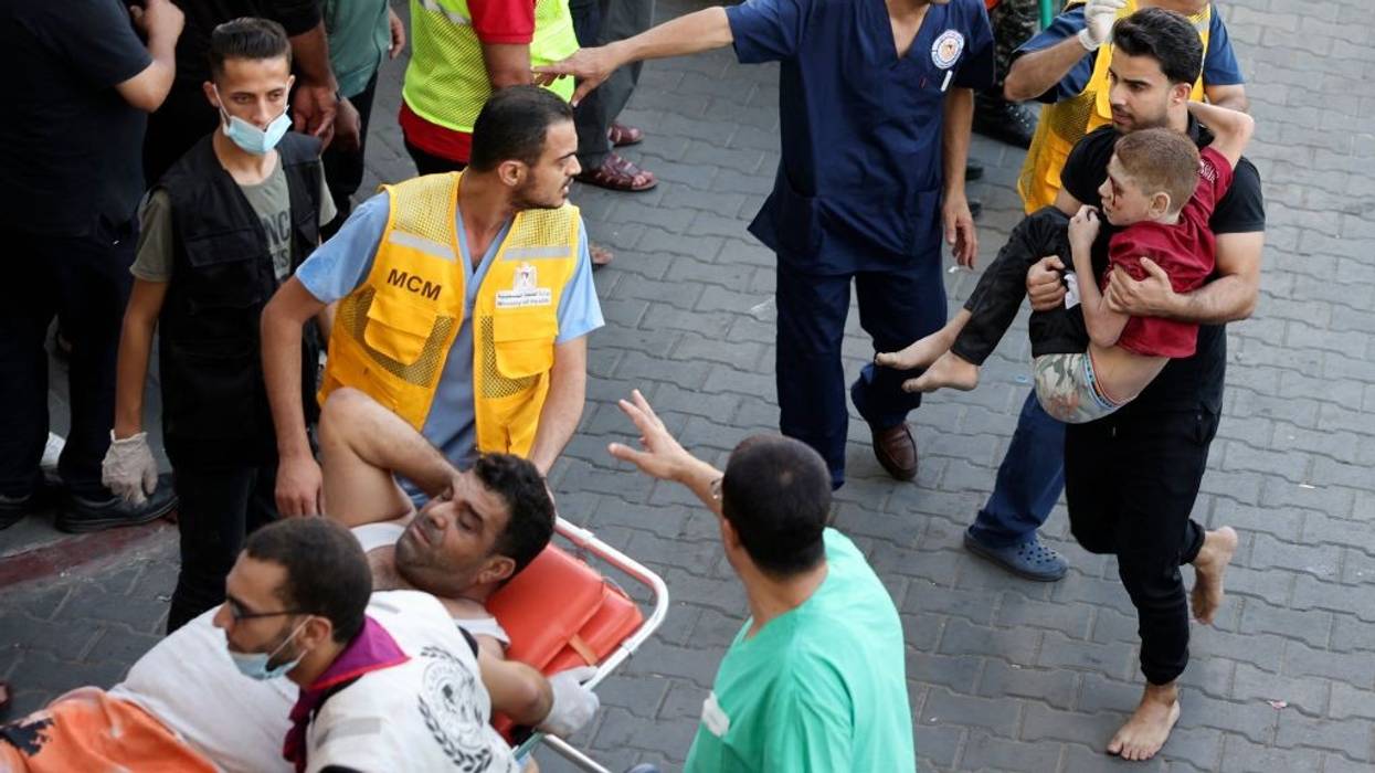 A man carries a child into a hospital in Gaza as medical workers rush around.