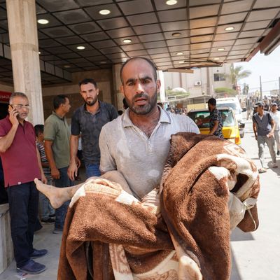 A man carries a child wrapped in a blanket at Nasser Hospital