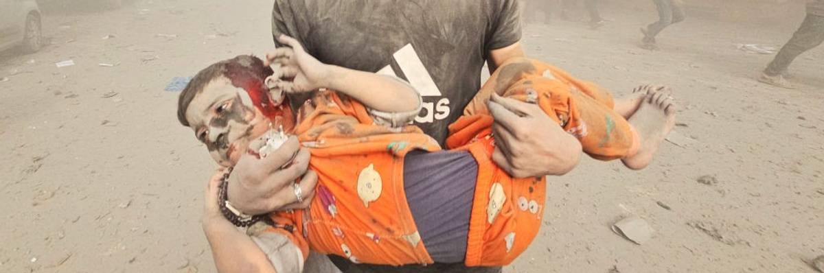 A man carries an injured Palestinian child after Israeli attack on Jabalia refugee camp in Gaza