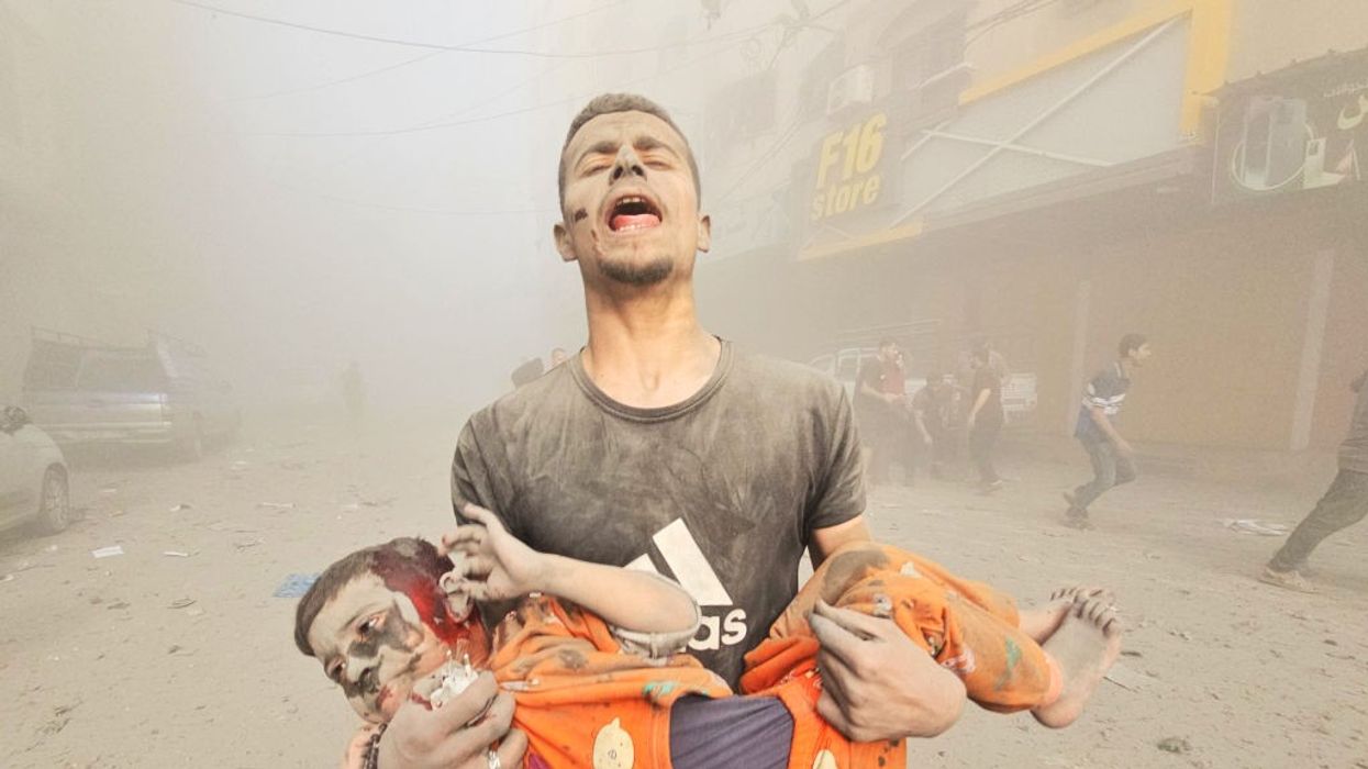 A man carries an injured Palestinian child after Israeli attack on Jabalia refugee camp in Gaza