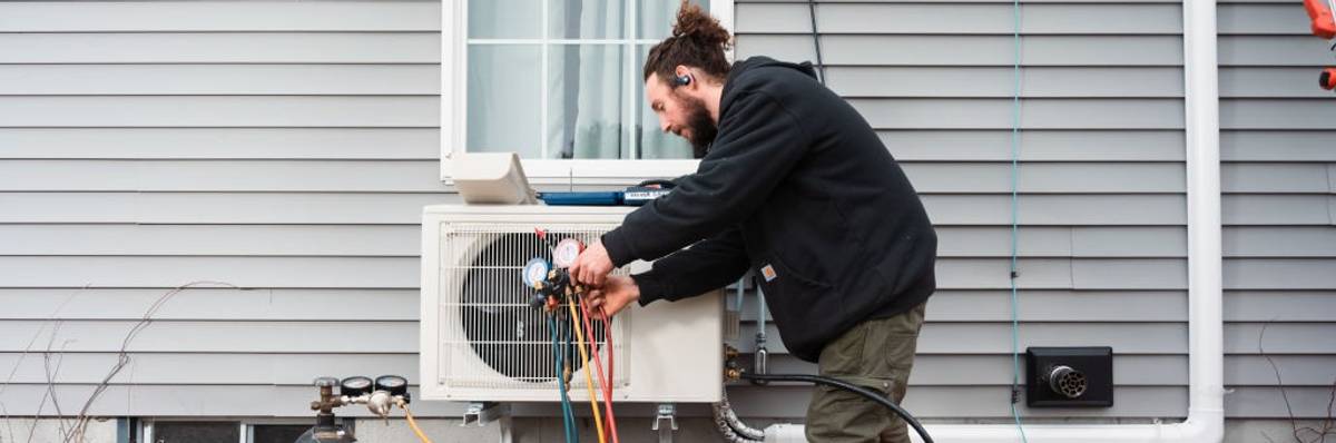 A man cleans moisture from a heat pump.