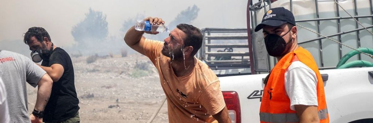 A man cools his face with a water bottle amidst wildfire smoke.