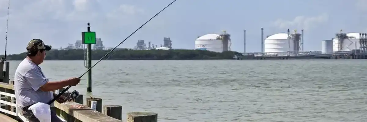 A man fishes near an LNG facility.