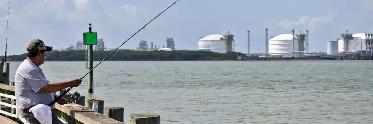 A man fishes near an LNG facility.