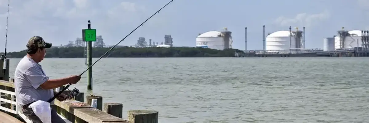 A man fishes near an LNG facility.