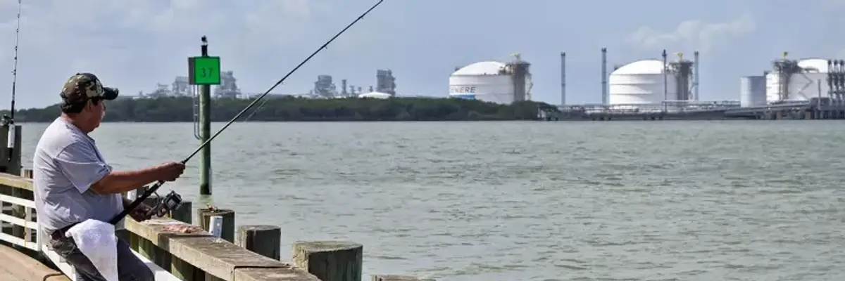 A man fishes near an LNG facility.