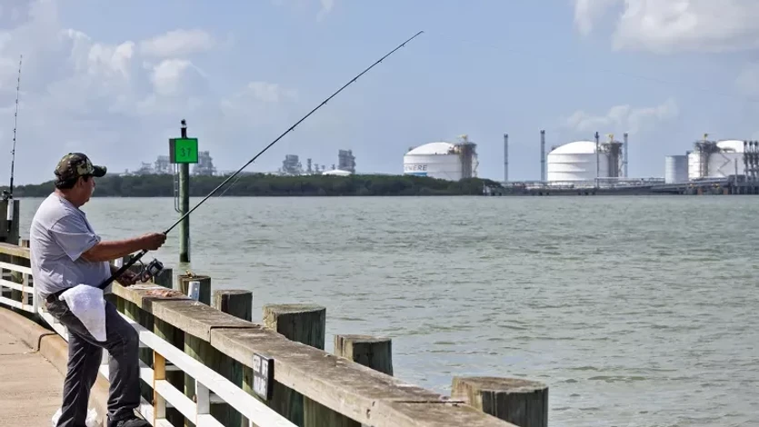 A man fishes near an LNG facility.