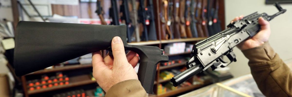 a man holds a bump stock accessory and an AK-47