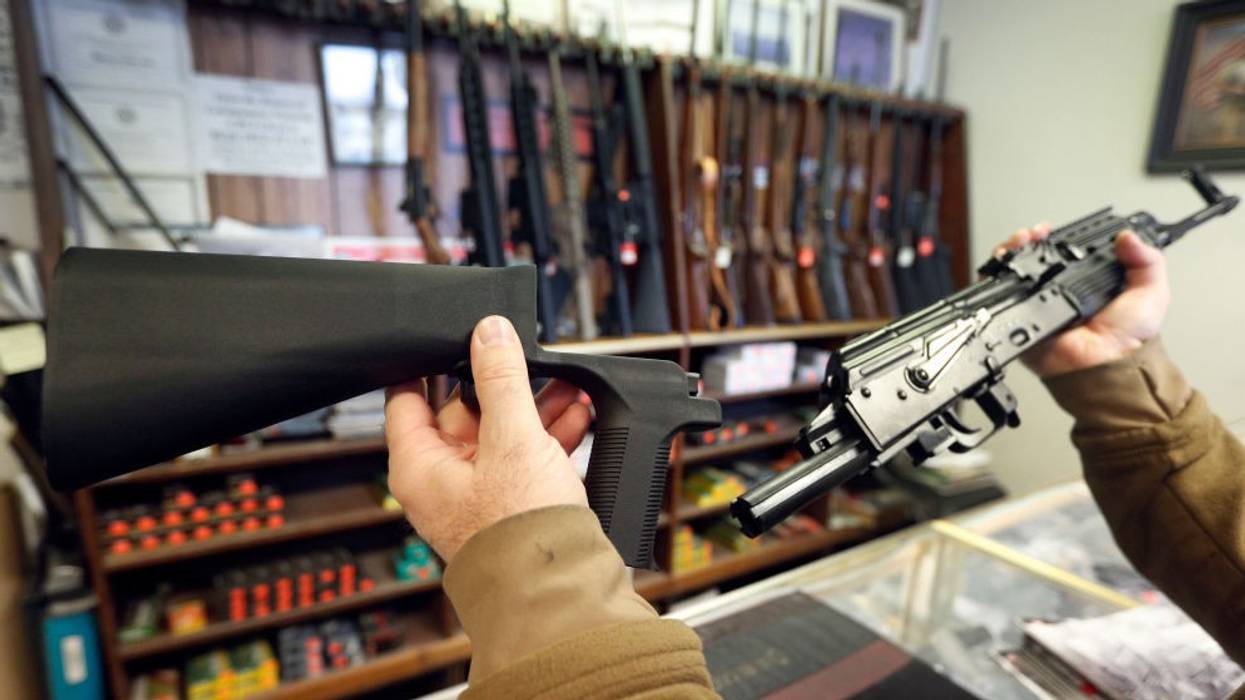 a man holds a bump stock accessory and an AK-47