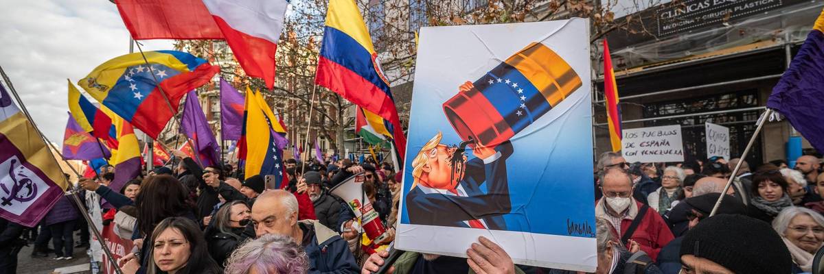 A man holds a placard during a protest showing US President Trump drinking oil.