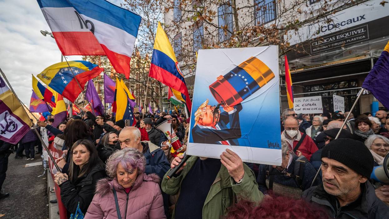 A man holds a placard during a protest showing US President Trump drinking oil.