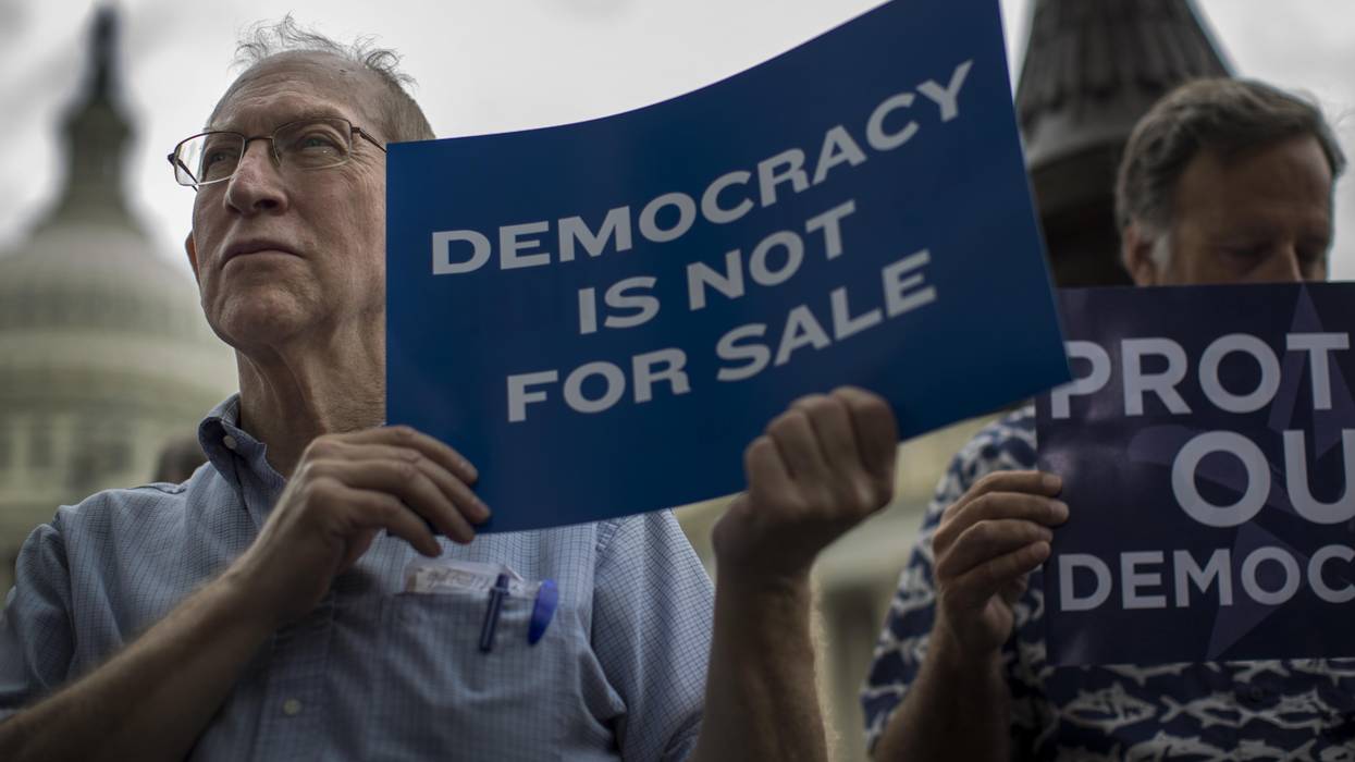 A man holds a sign reading, "Democracy is not for sale."