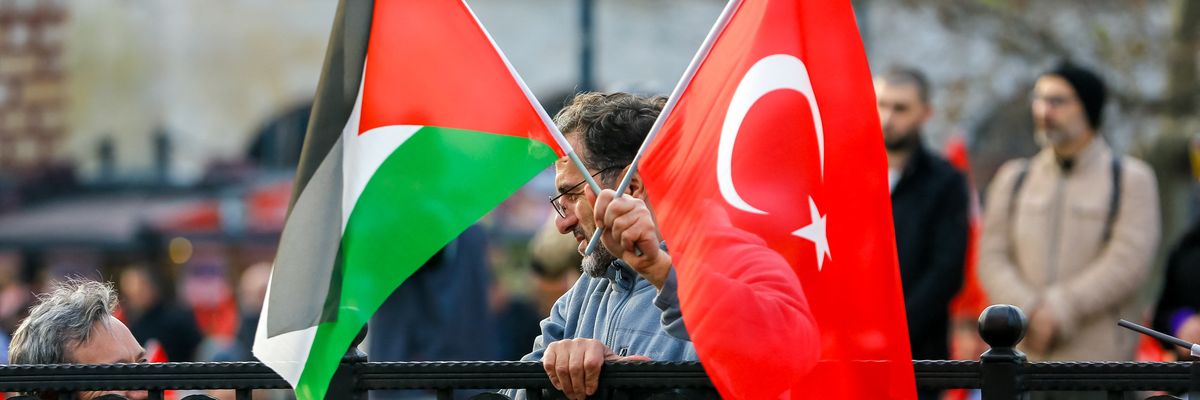 A man holds both Palestinian and Turkish flags