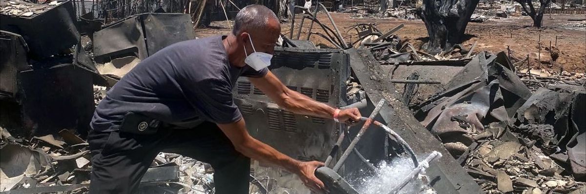 A man in a face mask removes items from the ashes of his home.