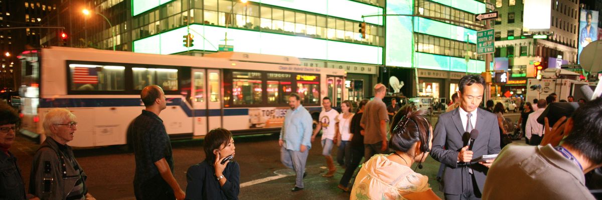 A man in a suit speaks into a microphone outside Lehman Brothers.