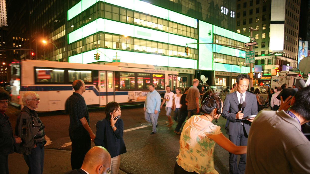 A man in a suit speaks into a microphone outside Lehman Brothers.
