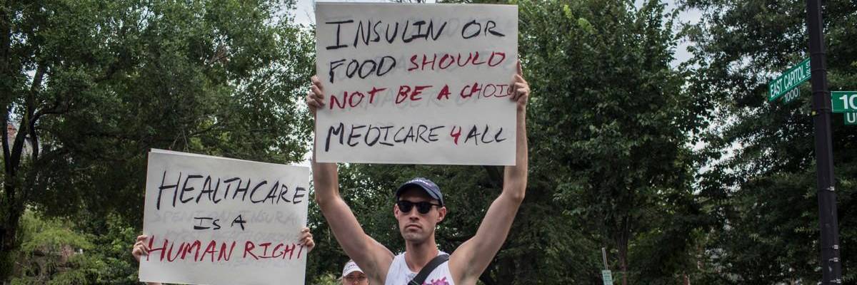 A man in a tank top holds up a sign reading, "Insulin or food should not be a choice. Medicare 4 All."