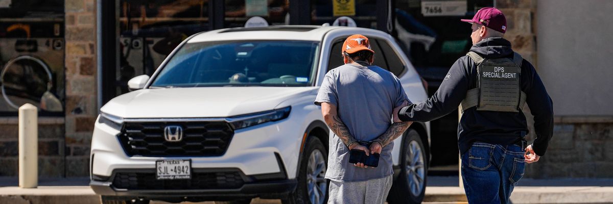 A man is detained by federal agents as Immigration and Customs Enforcement conducts raids