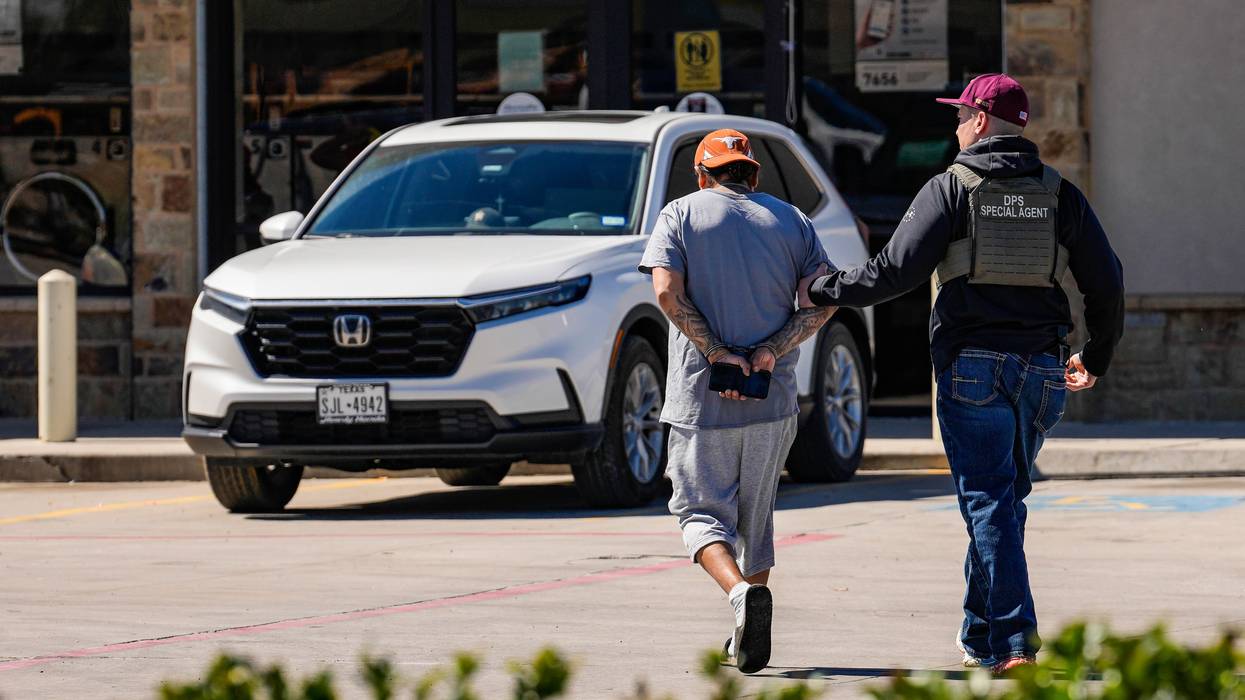 A man is detained by federal agents as Immigration and Customs Enforcement conducts raids