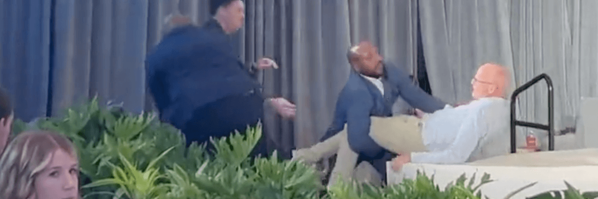 A man is dragged off a stage.