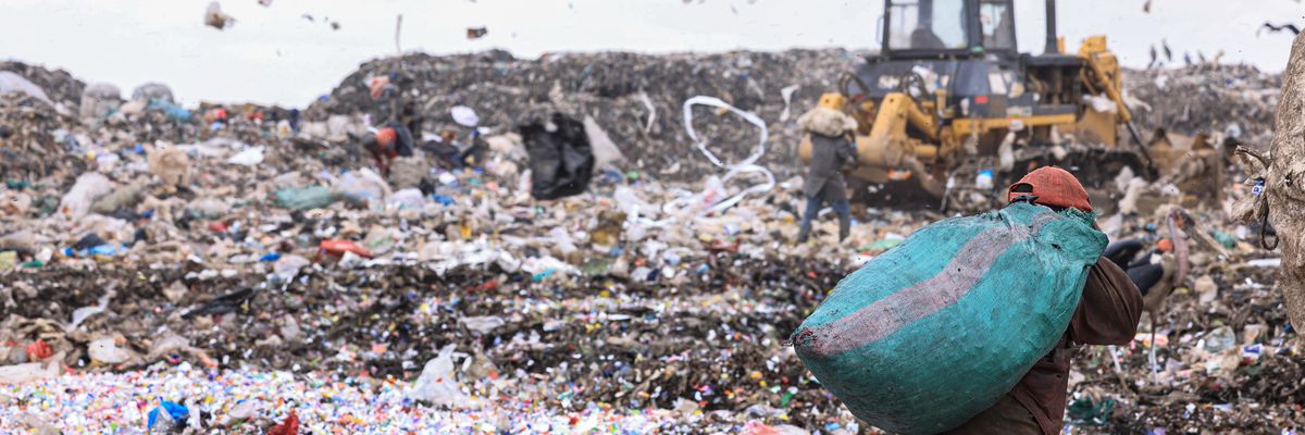 A man is seen carrying recyclables as plastic papers are blown by wind