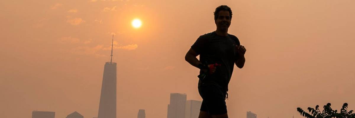 A man jogs in wildfire smoke with NYC in the background.