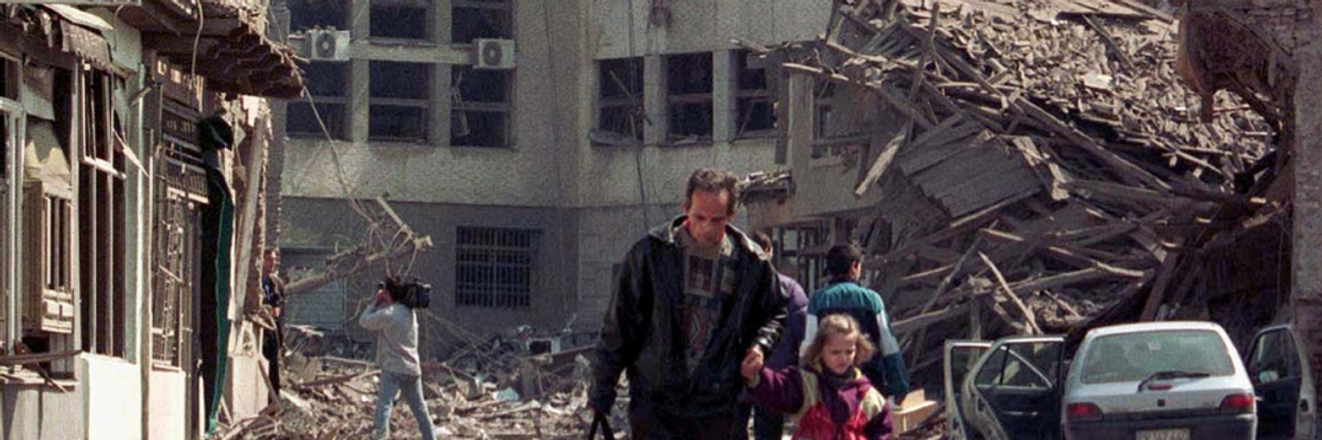 A man leads his daughter away from destroyed buildings