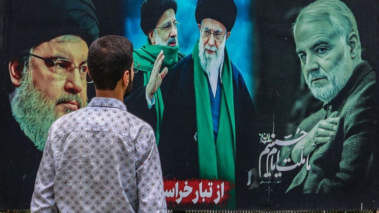 A man looks at a billboard featuring Iranian and Hezbollah leaders.