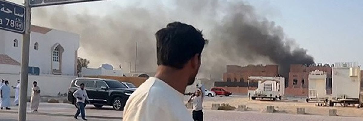 A man looks at smoke billowing after explosions