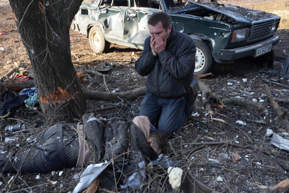 A man mourns near a body as airstrike damages an apartment complex outside of Kharkiv, Ukraine on February 24, 2022. (Photo: Wolfgang Schwan/Anadolu Agency via Getty Images)
