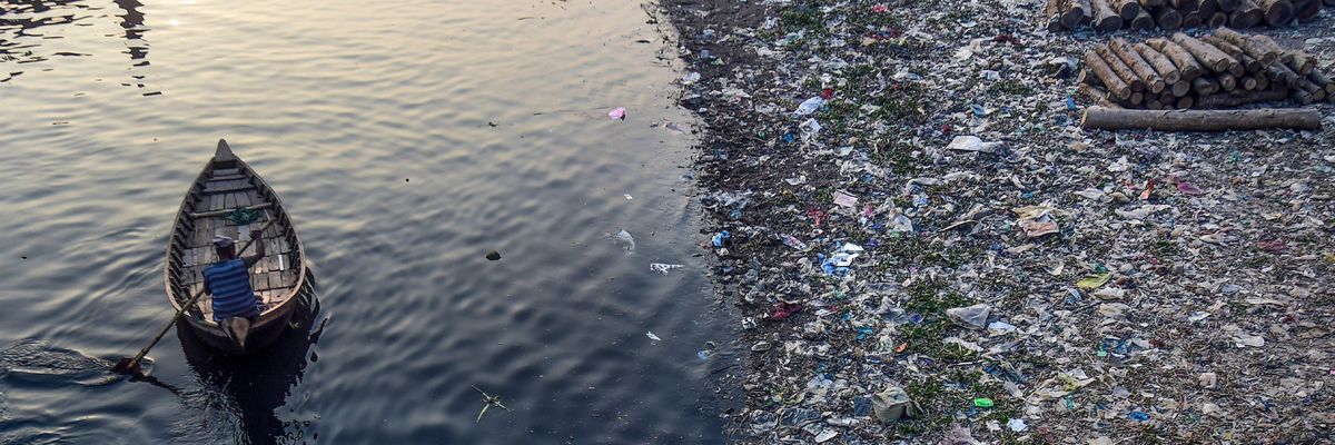 A man paddles on a boat as plastic bags float on the surface of the Buriganga River in Dhaka, Bangladesh on January 21, 2020.