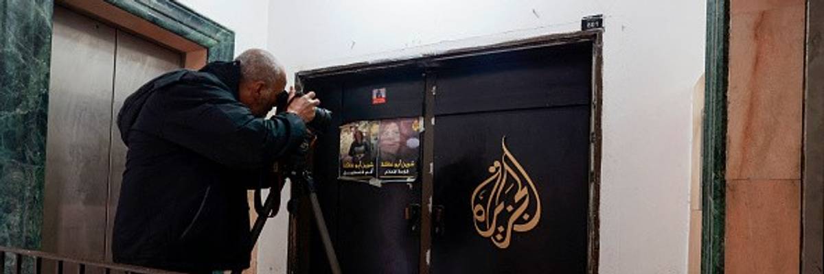 A man photographs the closed door of the Doha-based Al-Jazeera TV channel in the occupied-West Bank city of Ramallah.