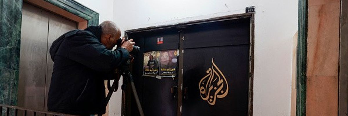 A man photographs the closed door of the Doha-based Al-Jazeera TV channel in the occupied-West Bank city of Ramallah.