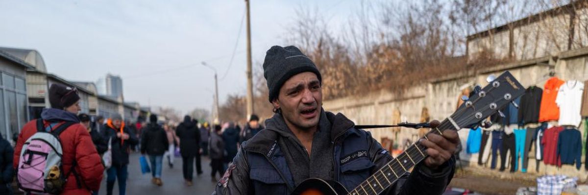 A man plays the guitar as vendors and shoppers gather at a market in Kyiv
