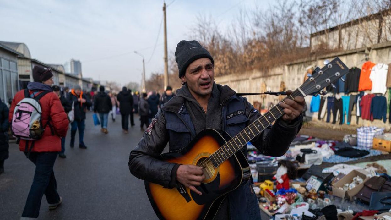 A man plays the guitar as vendors and shoppers gather at a market in Kyiv