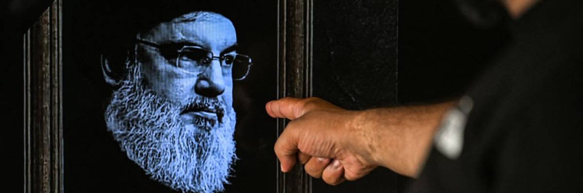 A man points to a television set displaying an image of the late leader of Hezbollah Hassan Nasrallah