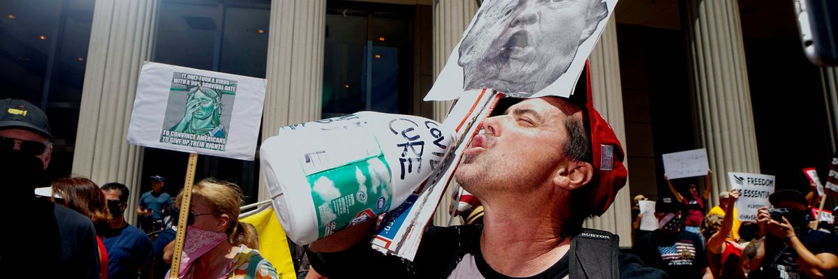 A man pretends to drink bleach during a protest against COVID restrictions in 2020.