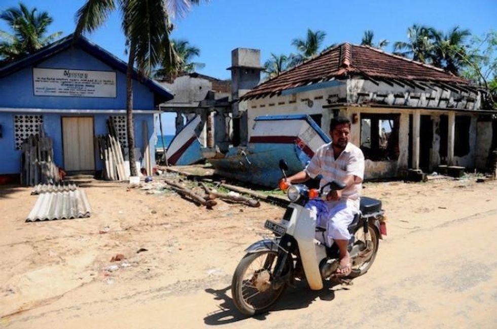A man rides his bike by houses destroyed by the tsunami in the Karathivu area in Kalmunai. (Photo: Amantha Perera/IPS)