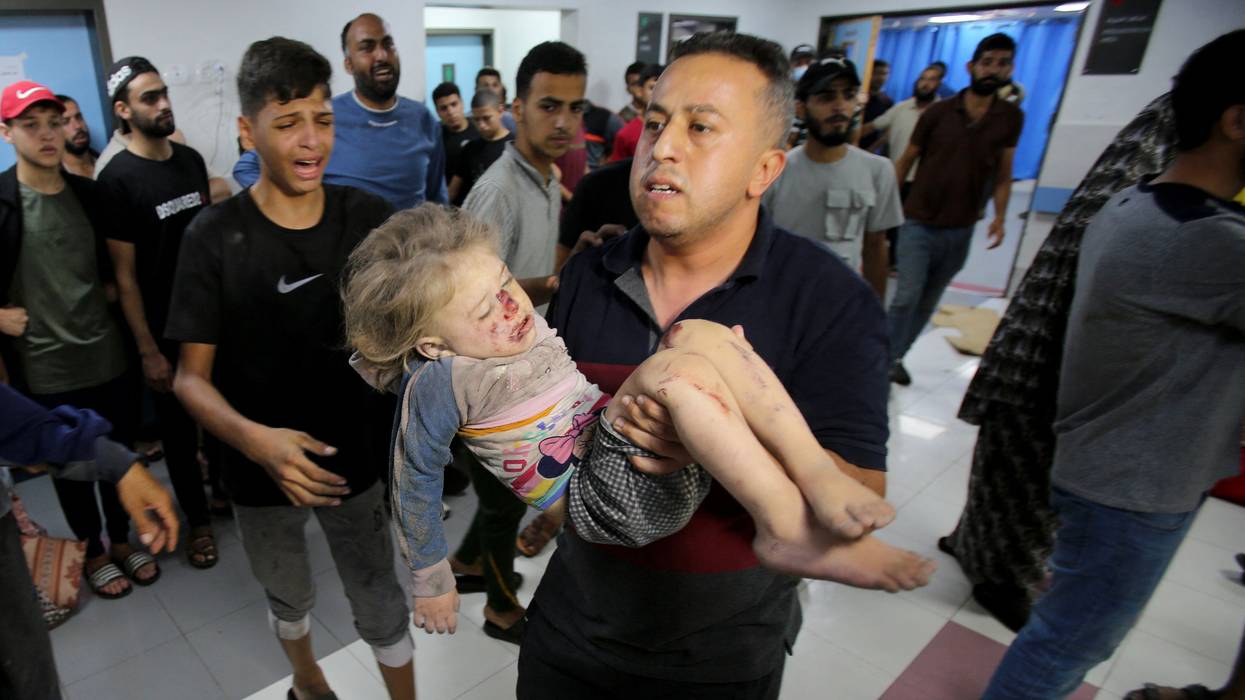 A man rushes a child into the al-Shifa Hospital