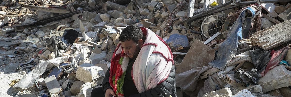 A man sits on the debris of collapsed buildings