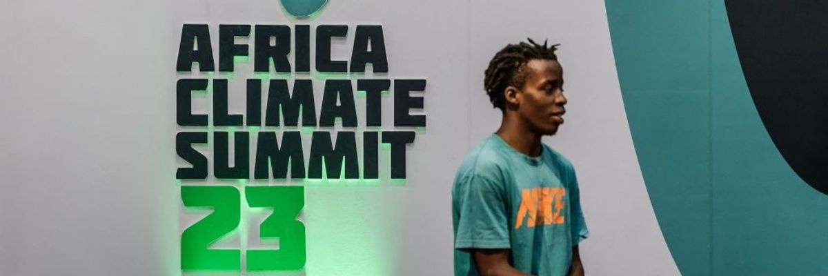 A man stands in front of the Africa Climate Summit 23 logo.