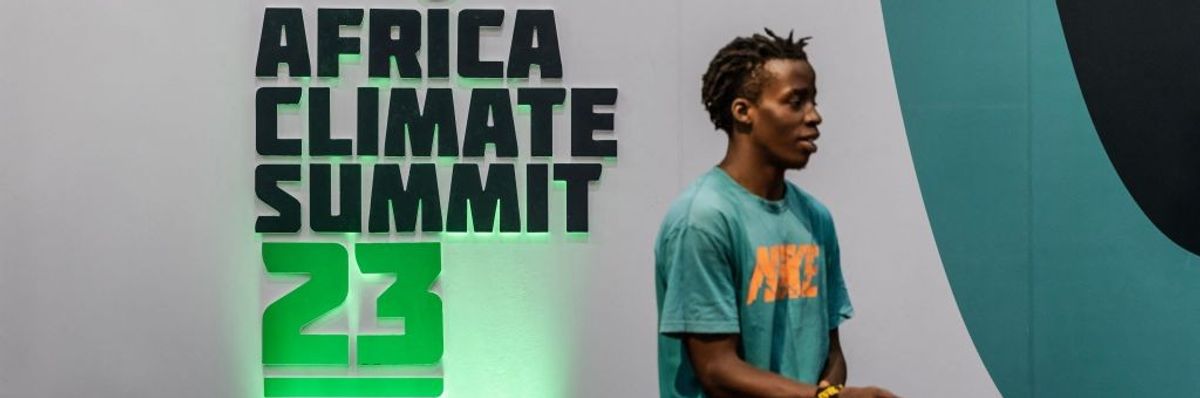 A man stands in front of the Africa Climate Summit 23  logo.
