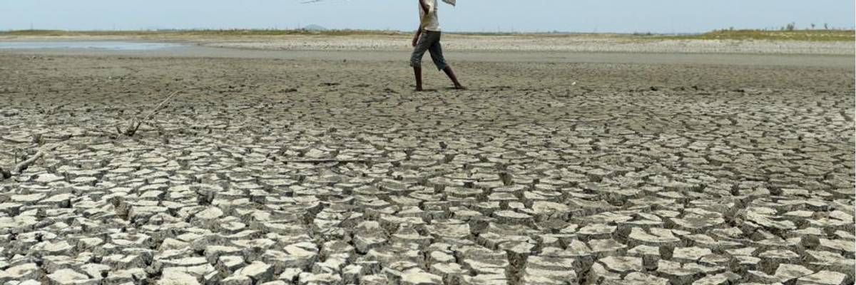 A man walks over the parched bed of a reservoir on the outskirts of Chennai, India on May 17, 2017. (Photo: Arun Sankar/AFP via Getty Images)